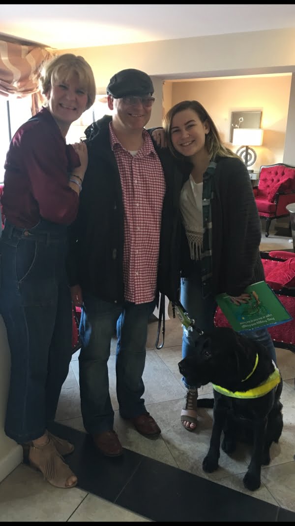 Jo, Colin, Molly and Guidedog Unis standing together smiling and looking at the camera.
