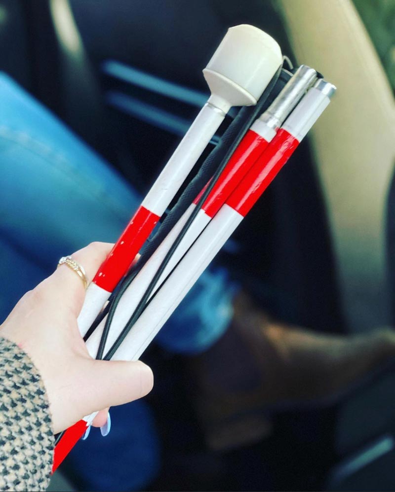 A folded white cane with red and white stripes.